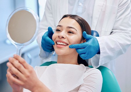 Woman smiling at reflection in handheld mirror