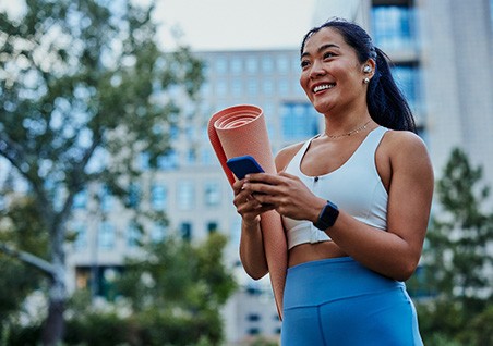 Smiling woman walking on park with workout mat