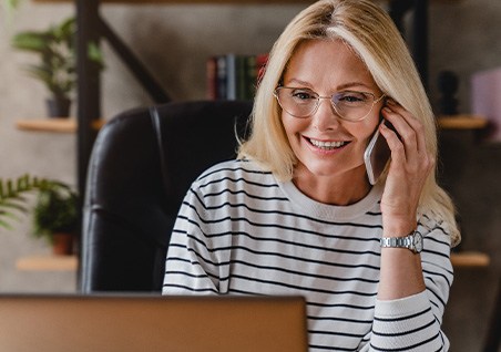 Woman with glasses smiling while talking on phone