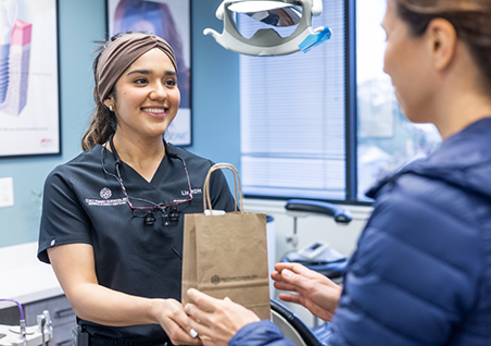 Woman in dental chair grinning up at her dentist