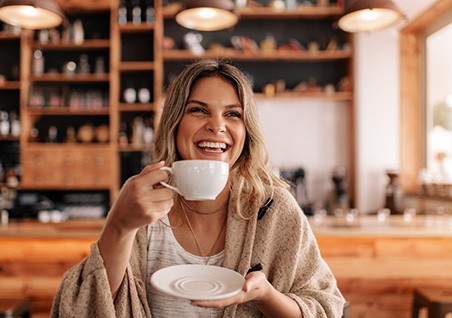 Woman smiling while enjoying coffee at restaurant