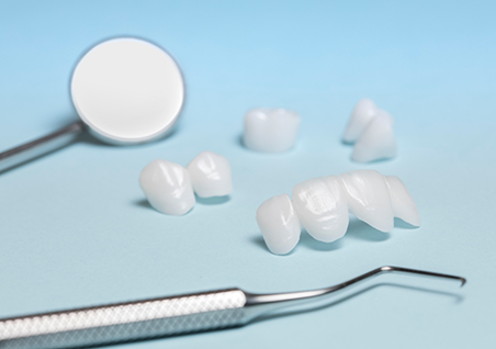 Several white dental crowns and veneers next to a dental mirror