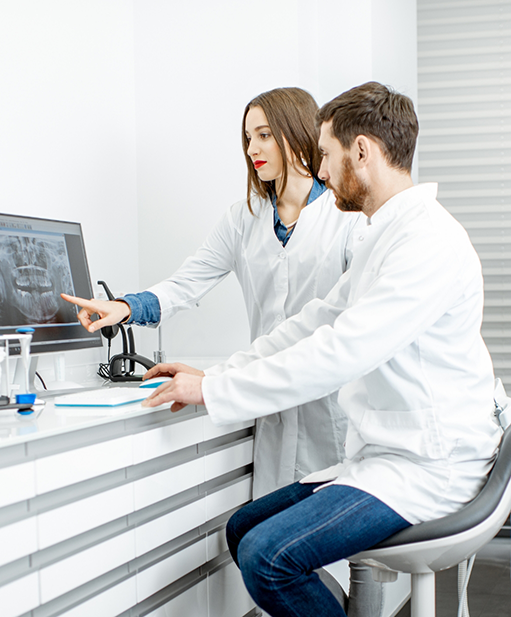 Two dentists looking at x rays of teeth on a computer