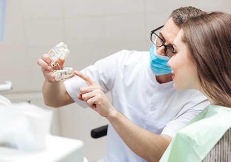 Dentist showing model replacement teeth to patient