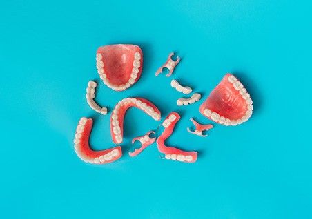 Bird’s eye view of several sets of full and partial dentures on blue background