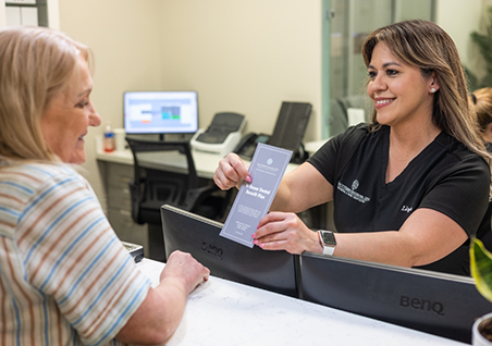Dental team member and patient looking at a form on a clipboard together