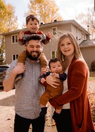 Family of four smiling in their front yard