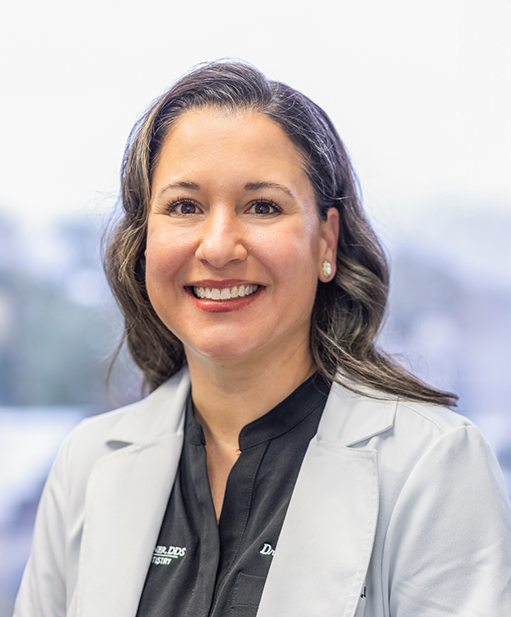 Bellaire dentist Doctor Stacy Hebert Schoener smiling in a white lab coat