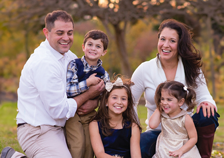 Doctor Stacy sitting in the grass with her husband and their three children