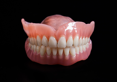 Set of full dentures against a black background