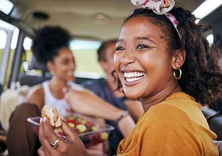Woman smiling while eating lunch in car with friends