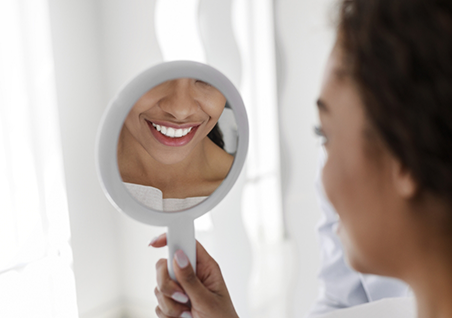 Dental patient looking at her white teeth in a mirror