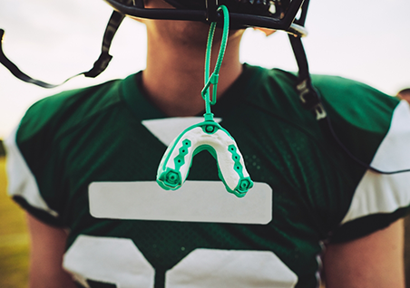 Football player with a mouthguard hanging from their helmet