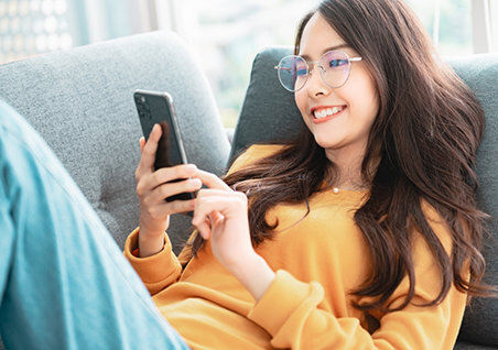 Young woman smiling while scrolling on her phone