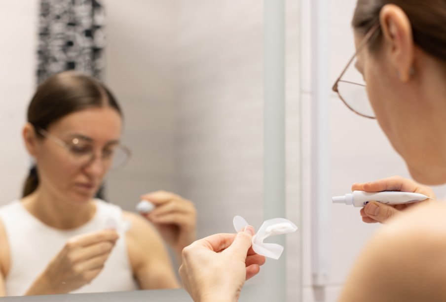 Woman applying DIY teeth whitening tray